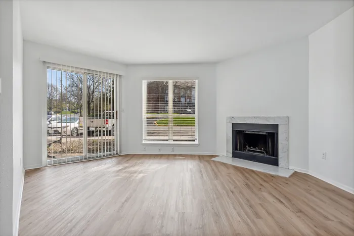Bright living room with elegant hardwood flooring, large windows for natural light, and a cozy fireplace, perfect for relaxation.
