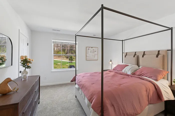 Elegant bedroom at ReNew Howard Crossing with a stylish four-poster bed, large window providing natural light, and chic decor for a cozy ambiance.