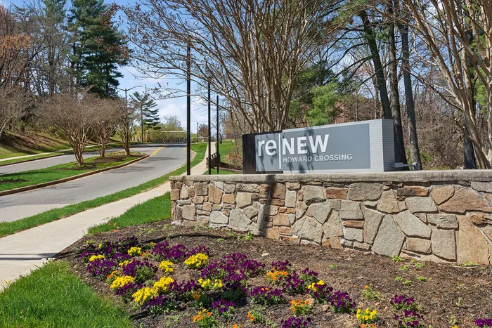 Charming entrance of ReNew Howard Crossing with vibrant flower beds and lush greenery, offering a welcoming and serene ambiance.