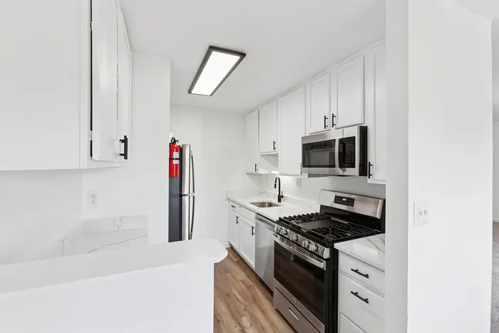 Modern kitchen at ReNew Howard Crossing  with sleek appliances, bright lighting, and elegant white cabinetry.