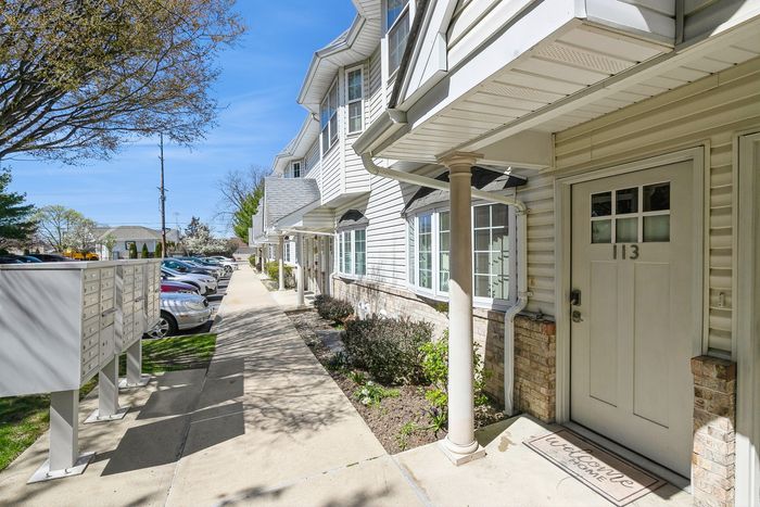 Charming townhouse exterior with classic brick accents, inviting entrance, and a well-maintained sidewalk on a sunny day.