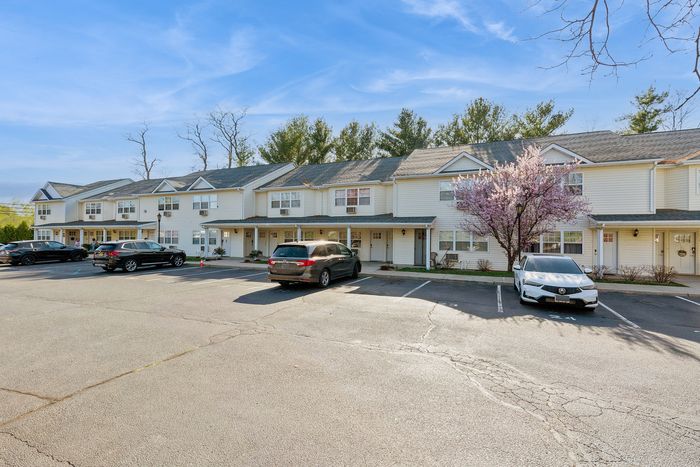 Charming suburban townhouses with blooming cherry blossom tree and ample parking, showcasing modern living in a serene setting.