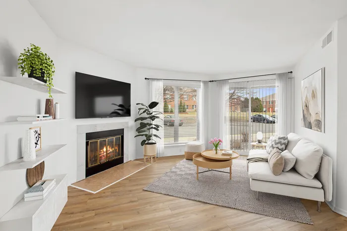 Bright, contemporary living room with a cozy fireplace, chic furnishings, and large windows offering a charming view.