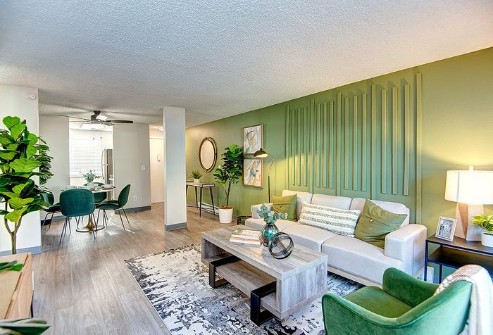 Bright open-concept living room and dining room with modern furniture and green accent wall at ReNew Dash Point.