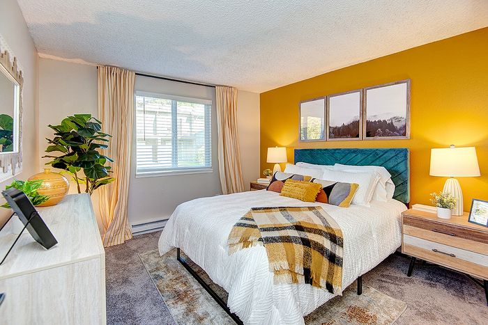 Bright bedroom with yellow accent wall and queen sized bed at ReNew Dash Point.