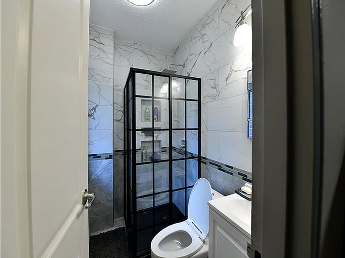ReNew Bristol Modern Bathroom with Marble Walls, Glass-Door Shower, and Upgraded Lighting.