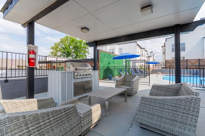 Chic outdoor lounge with modern wicker furniture, BBQ grill, and inviting poolside ambiance; perfect for relaxing and entertaining.