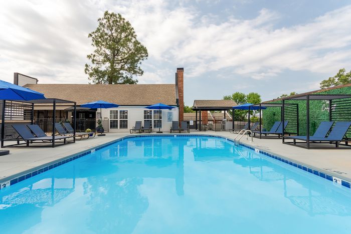 Inviting outdoor swimming pool with luxurious lounge chairs and vibrant blue umbrellas, perfect for relaxation under sunny skies.