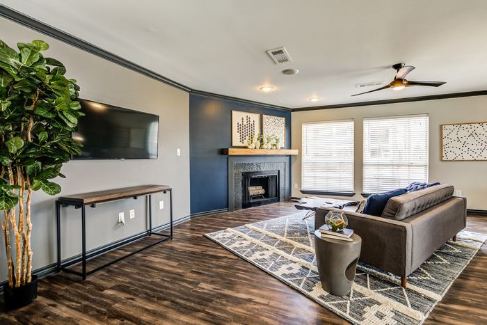 Elegant living room with modern decor featuring a sleek wall-mounted TV, stylish sofa, and a cozy fireplace accented by tasteful art pieces and abundant natural light.