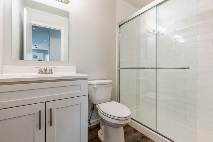 Bright modern bathroom with sleek glass shower, elegant white vanity, and polished chrome fixtures.