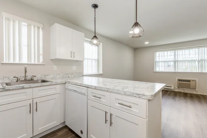 Elegant modern kitchen with marble countertops, stainless steel sink, and natural light from large windows.