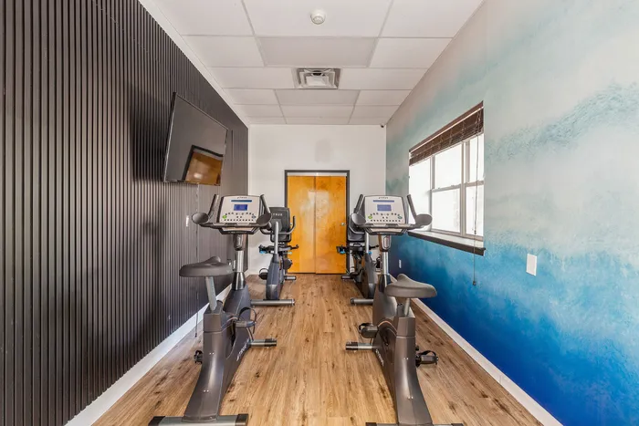 Modern, stylish fitness room with top-of-the-line stationary bikes and vibrant blue accent wall, perfect for energizing workouts.