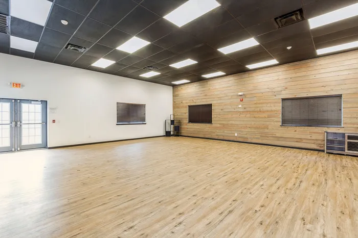 Spacious and versatile room with modern wood paneling, ideal for events or creative workshops, featuring sleek flooring and ample natural light.