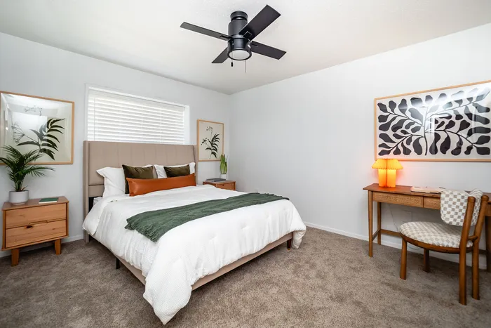 Elegant bedroom with a plush bed, modern ceiling fan, stylish decor, and calming neutral tones.