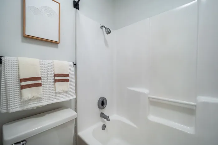 Chic modern bathroom showcasing a pristine white bathtub, elegant wall art, and stylishly folded towels for a luxurious touch.