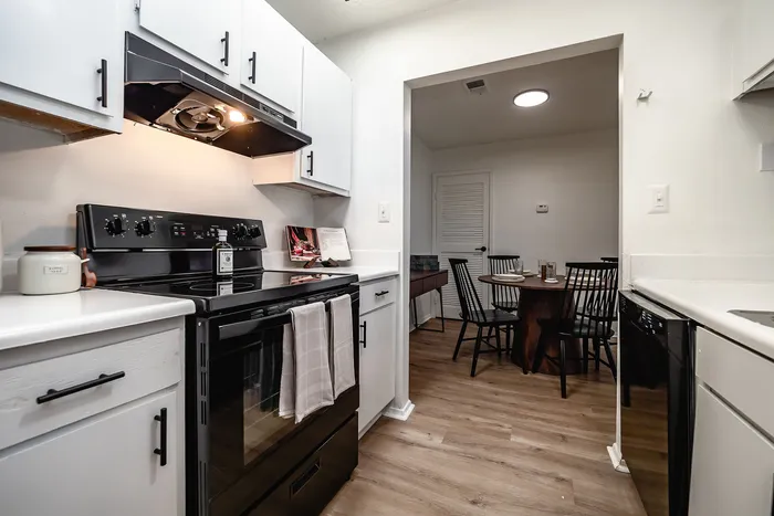 Modern kitchen with sleek black appliances, elegant white cabinetry, and a charming dining area for intimate gatherings.