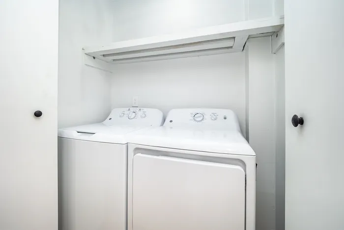 Compact laundry nook with modern washer and dryer, neatly tucked behind white closet doors.