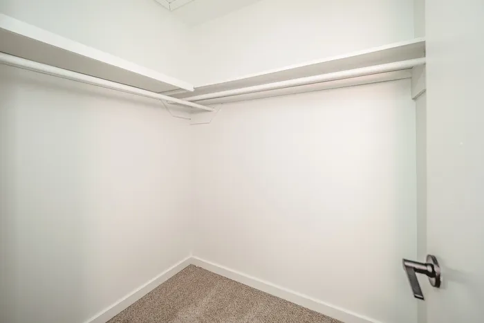 Spacious walk-in closet with sleek white shelving and ample storage space, perfect for organizing your wardrobe.