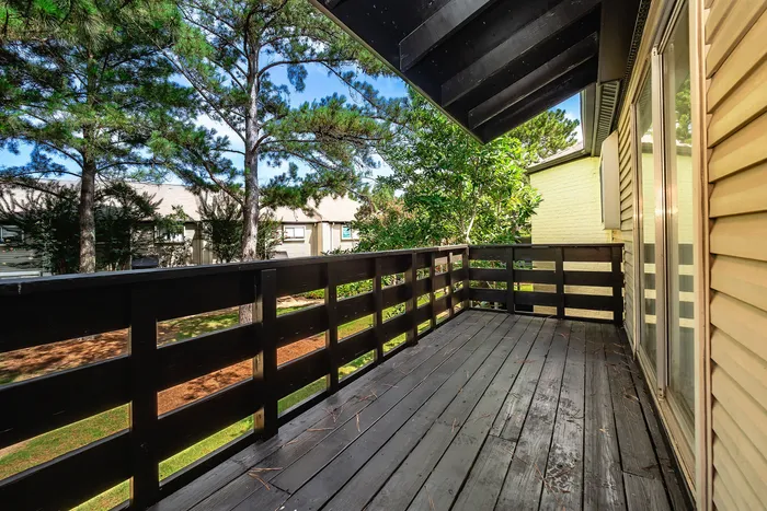 Inviting wooden balcony with scenic views of lush pine trees, perfect for relaxation and enjoying nature.
