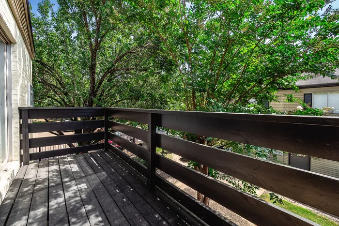 Inviting balcony with wooden railing, offering picturesque views of lush greenery, perfect for relaxing outdoors.