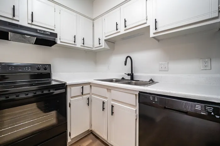 Modern kitchen with sleek black appliances, stylish white cabinetry, and elegant countertops.