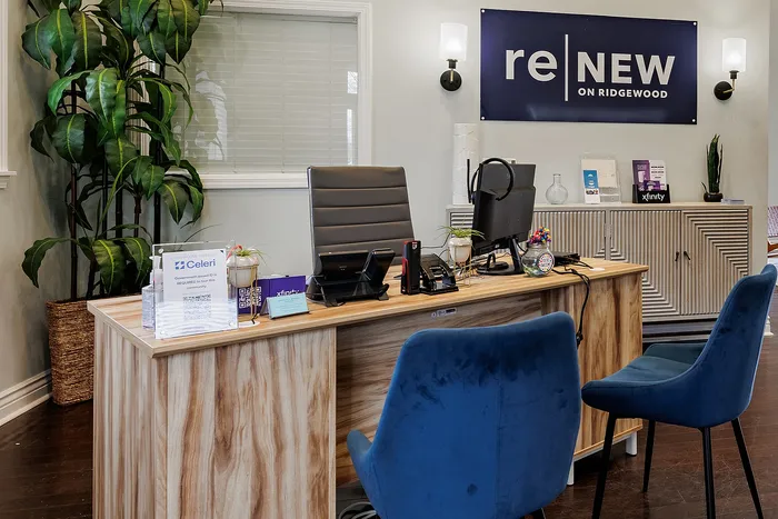 Welcoming leasing office at reNEW on Ridgewood, featuring stylish decor with modern furniture and vibrant green plants.