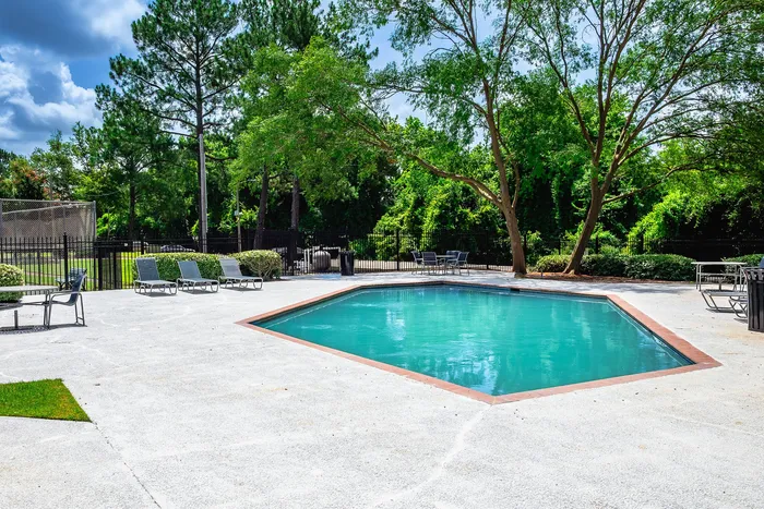 Inviting outdoor pool area with lush greenery and comfortable lounge chairs, perfect for relaxation and leisure.