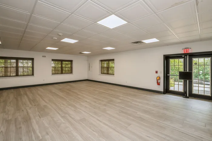 Spacious and bright room with elegant wood flooring, ample windows, and modern ceiling lights, ideal for versatile use.