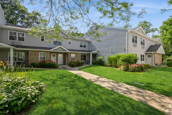 Charming residential building with lush green lawns and vibrant flowerbeds, offering a peaceful suburban appeal.