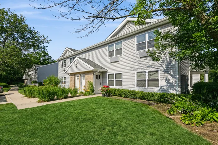 Charming suburban apartment building surrounded by lush greenery and well-maintained lawns, offering a peaceful and inviting ambiance.