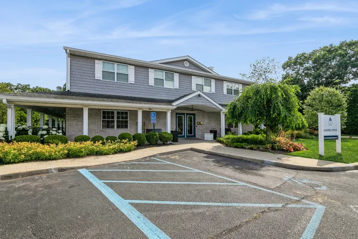 Charming two-story building with elegant landscaping and abundant greenery, featuring a welcoming entrance and accessible parking.