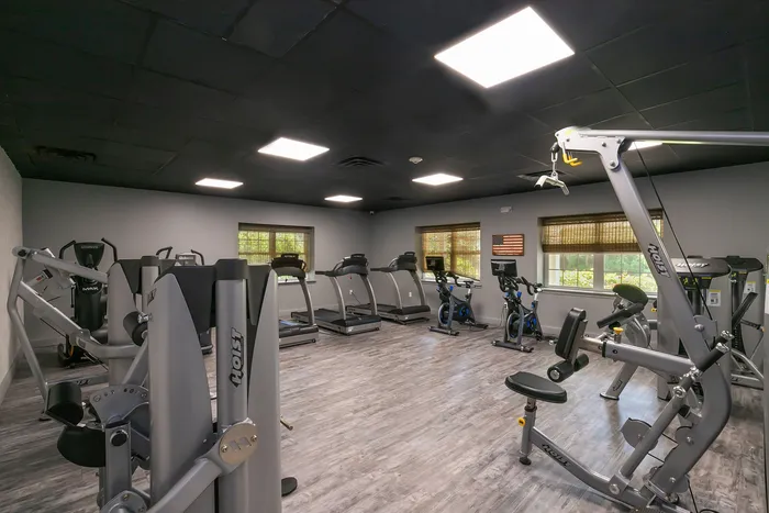 Modern fitness center featuring state-of-the-art exercise equipment, including treadmills, stationary bikes, and weight machines, in a spacious, well-lit room.
