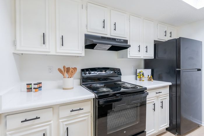 Sleek, modern kitchen with crisp white cabinetry, stylish black appliances, and elegant quartz countertops.