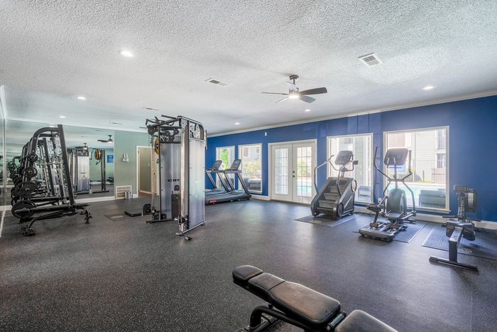 Modern fitness center with state-of-the-art equipment and bright natural lighting, offering a welcoming and energizing workout environment.