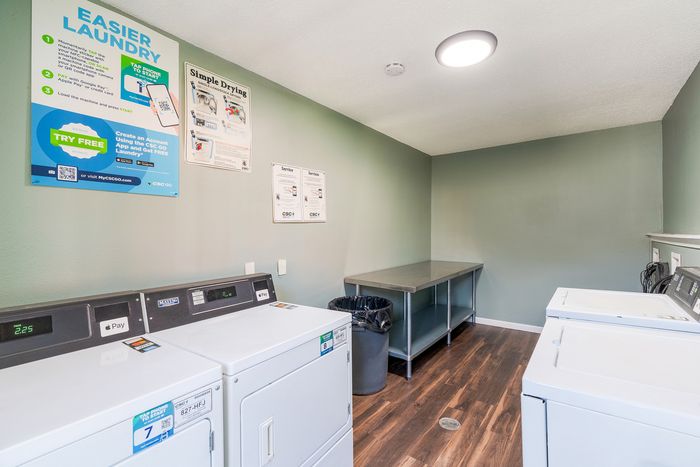 Modern laundry room equipped with convenient appliances, hardwood floors, and clean, bright walls, offering an efficient and easy cleaning experience.