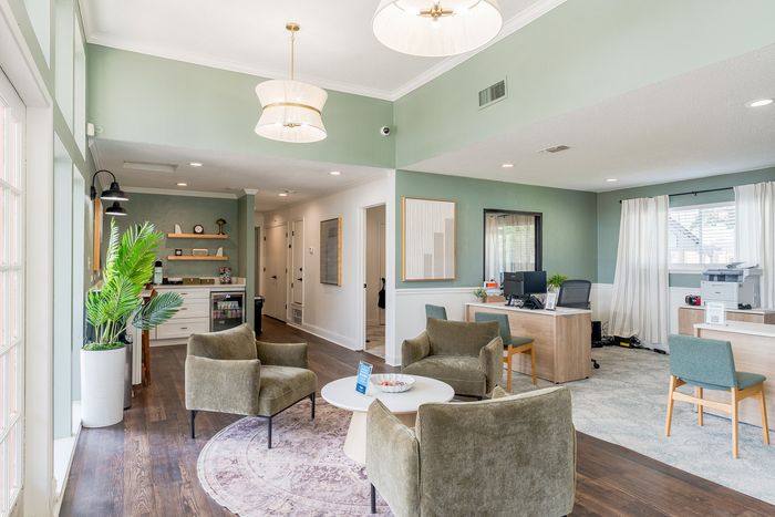 Chic and inviting lounge area with elegant green seating, modern pendant lighting, and large windows offering natural light.