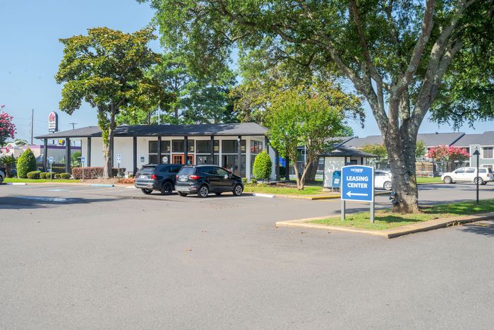 Inviting apartment leasing center surrounded by lush greenery and ample parking space.