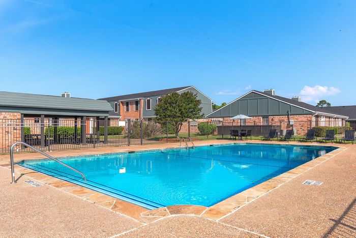 Inviting outdoor pool area surrounded by charming townhouses, perfect for relaxation and leisure.