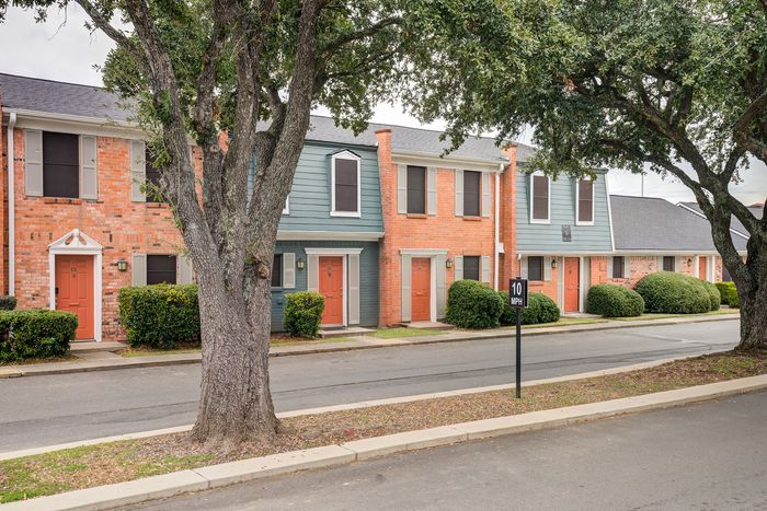 Charming suburban townhouses with vibrant red doors and lush greenery, offering a cozy and inviting neighborhood ambiance.