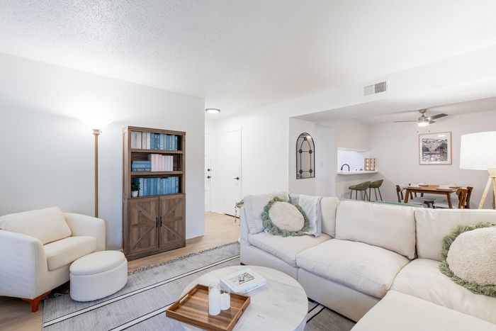 Inviting living space with plush sofa, cozy armchair, and elegant bookshelf in an open-concept layout.