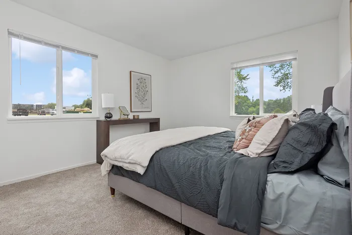 Bright bedroom showcasing a cozy bed with elegant bedding, large windows offering scenic views, and tasteful decor for a serene ambiance.