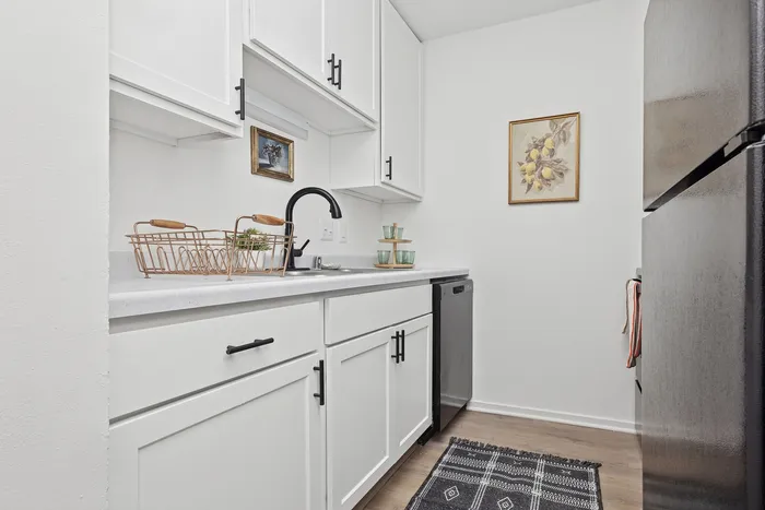 Modern kitchen with sleek white cabinets, stylish black fixtures, and contemporary art, featuring a cozy and inviting atmosphere.