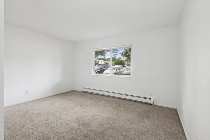Bright and inviting carpeted room with large window view, perfect for a cozy retreat or office space.
