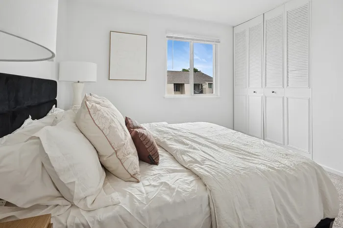 Bright and airy bedroom with modern furnishings, cozy bedding, and a scenic window view.