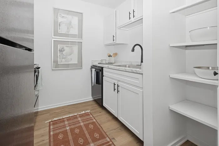 Chic and compact kitchen with modern white cabinetry, elegant marble countertop, and stylish open shelving.