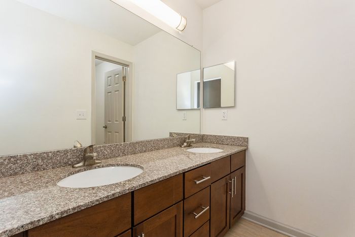 Modern bathroom with elegant granite countertops, dual sinks, and ample cabinet storage.