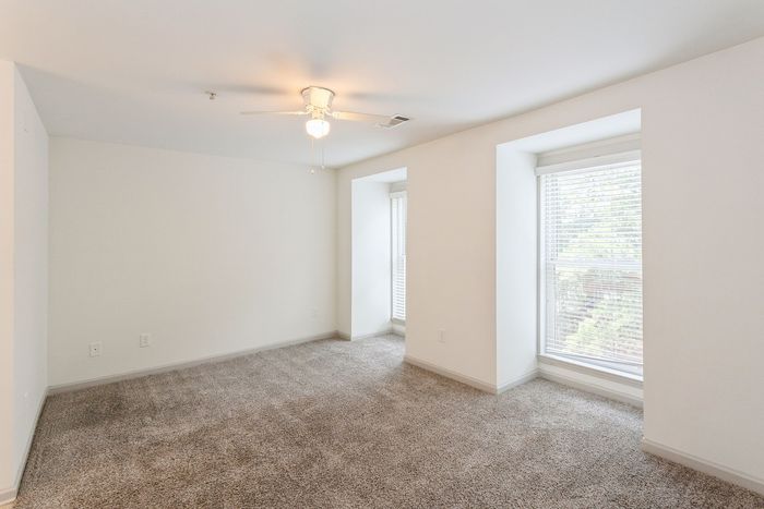 Bright and spacious bedroom with cozy carpet, white walls, and large windows inviting natural light.