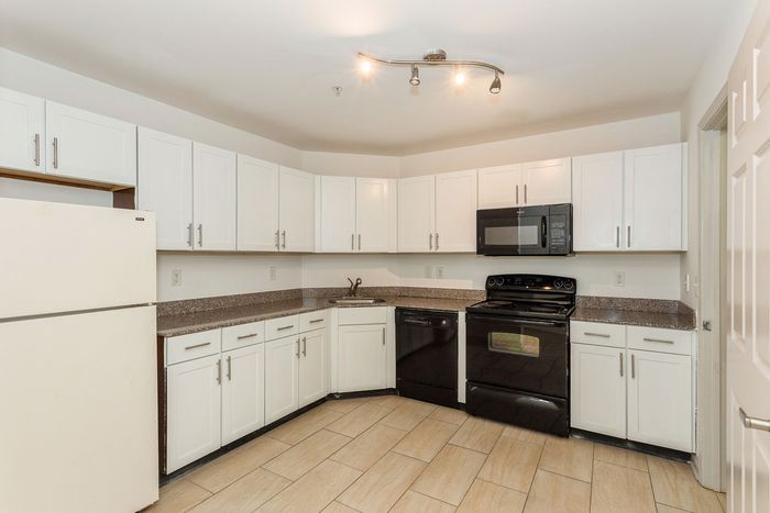 Modern kitchen with sleek white cabinets, granite countertops, and stainless steel appliances.