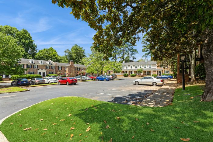 Charming residential housing with brick facades surrounded by lush greenery and ample parking space.