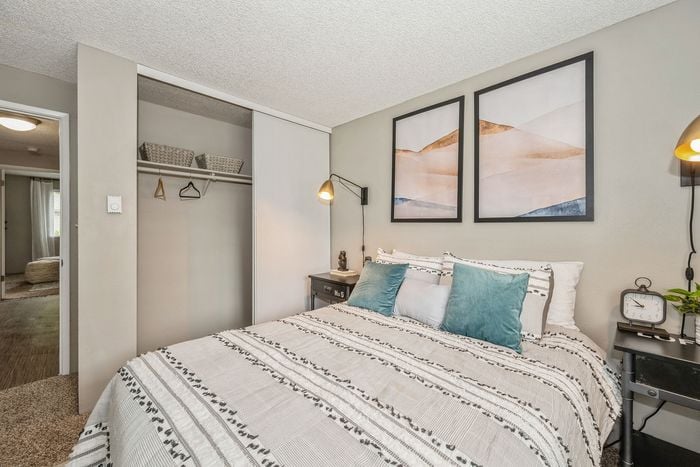 Inviting bedroom with cozy bedding, decorative throw pillows, modern wall art, and ample closet space.